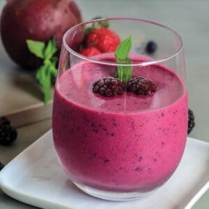 Glass filled with beet smoothie on a plate
