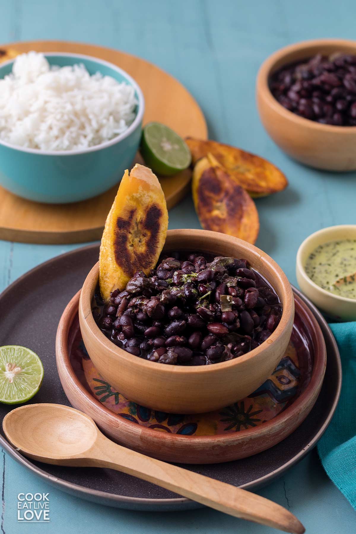 Cuban black beans served in a small wooden bowl with fried plantain garnish