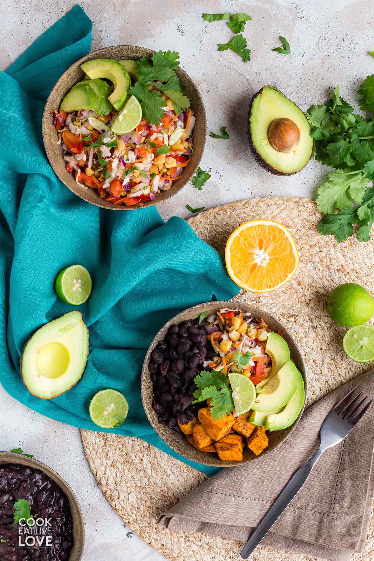 Black bean burrito bowl on the table with a bowl of citrus slaw.