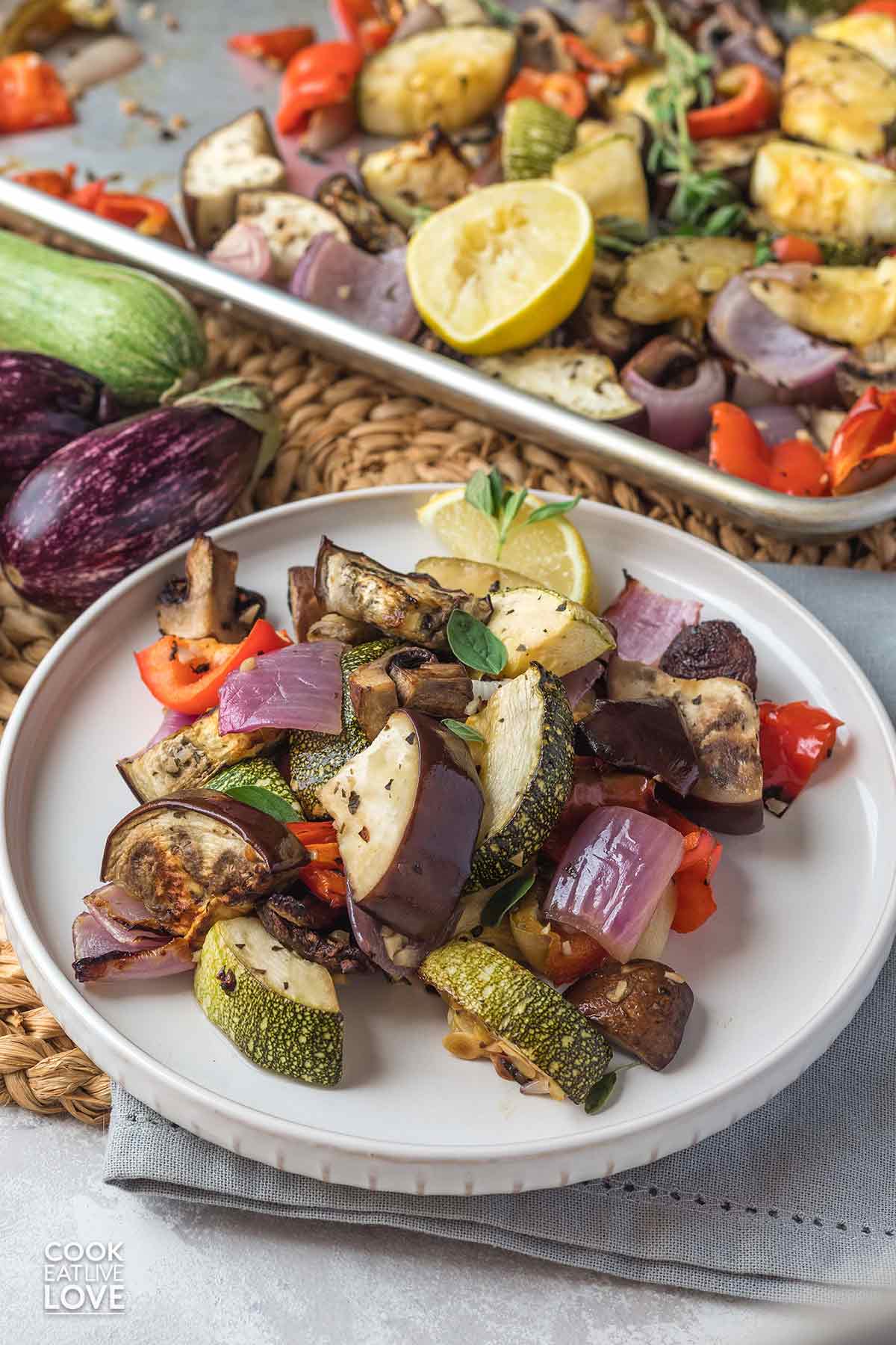 Mediterranean roasted vegetables on a plate and a baking sheet in the background.