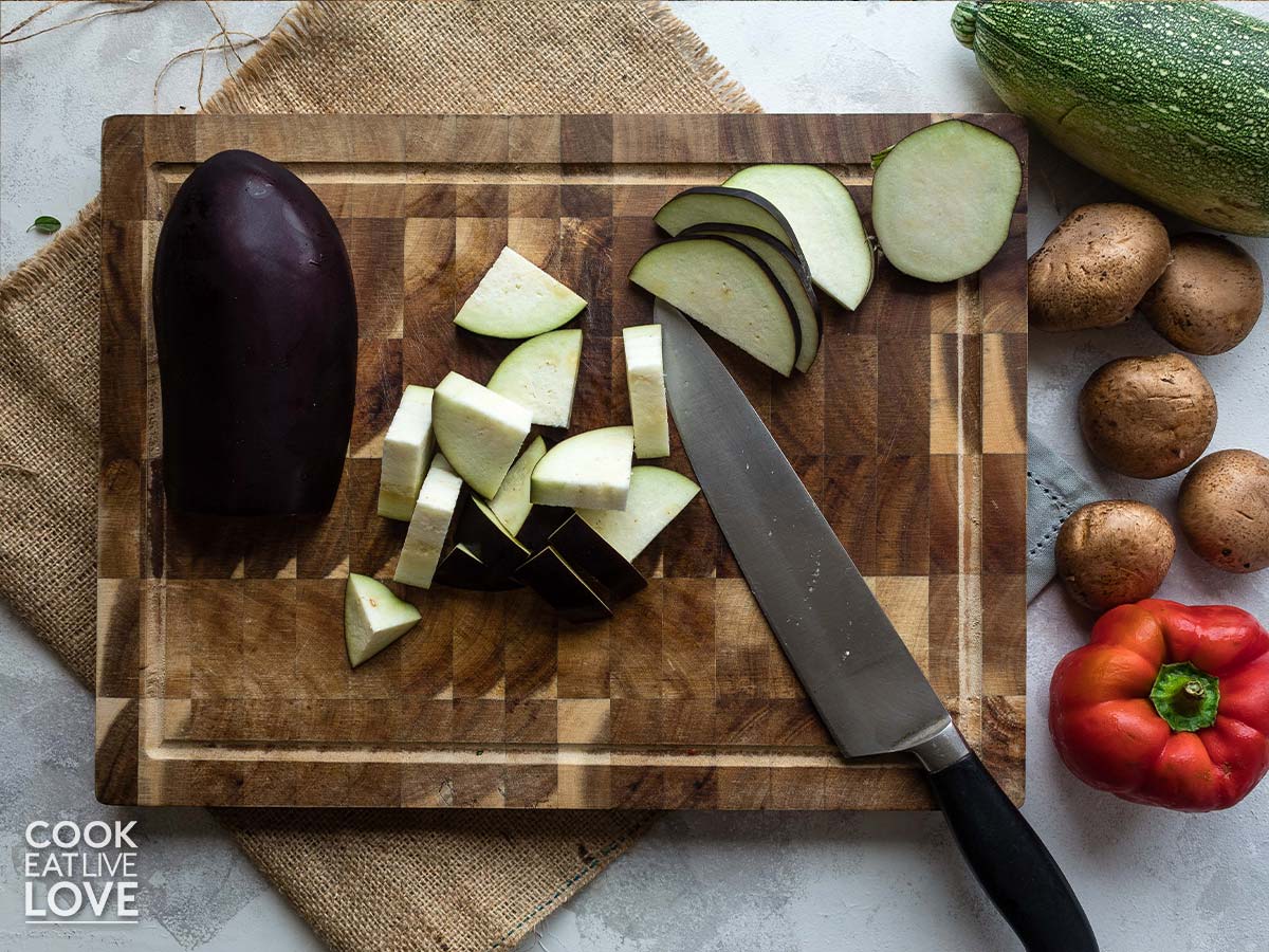 Eggplant cut into pieces on a cutting board.