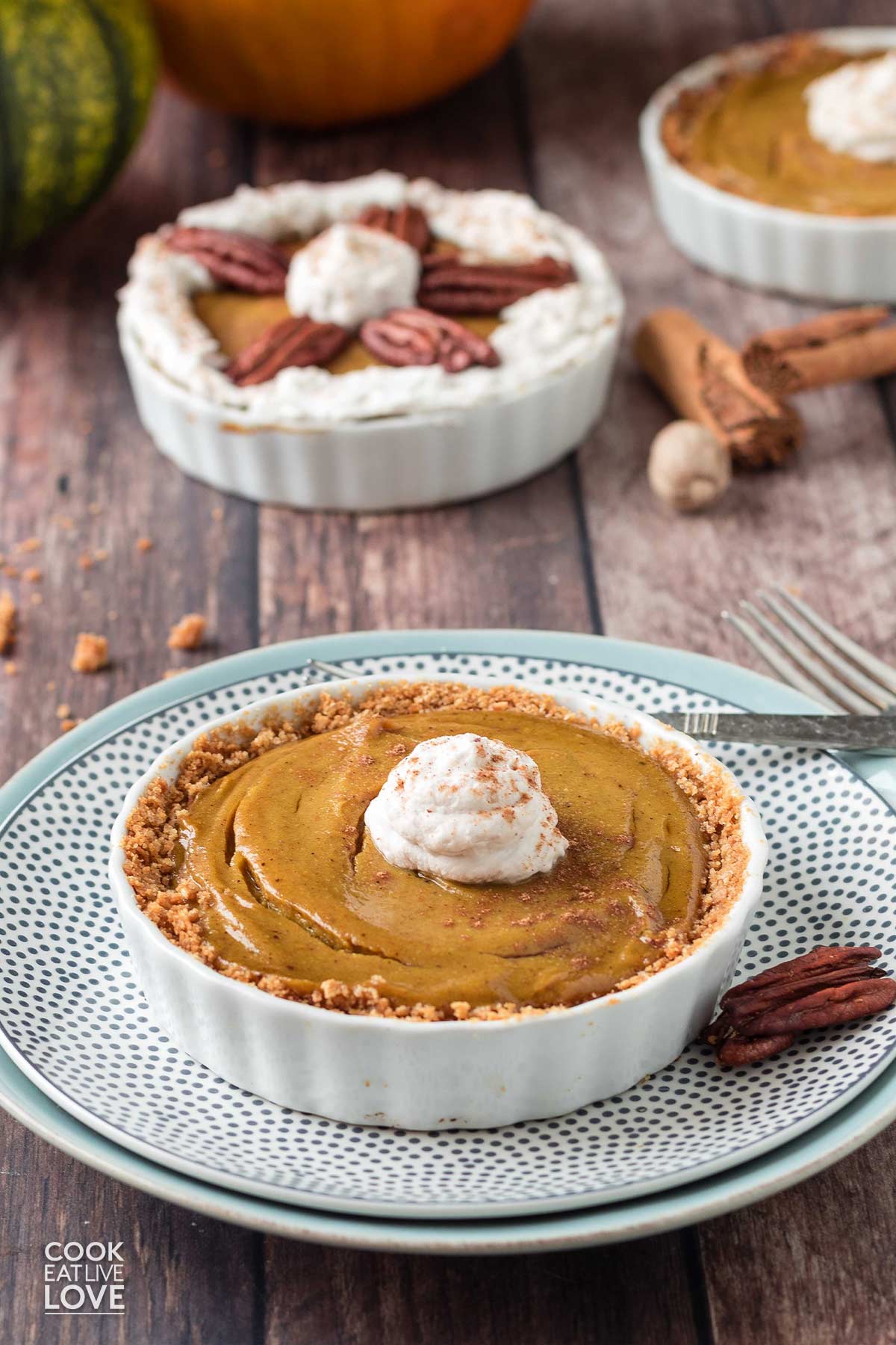 Individual eggless pumpkin pie baked in a ramekin on the table with pecans.
