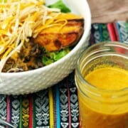 Turmeric dressing in a mason jar and salad on a bowl on a table