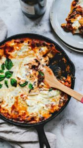 Skillet of Lasagna with wooden spoon.