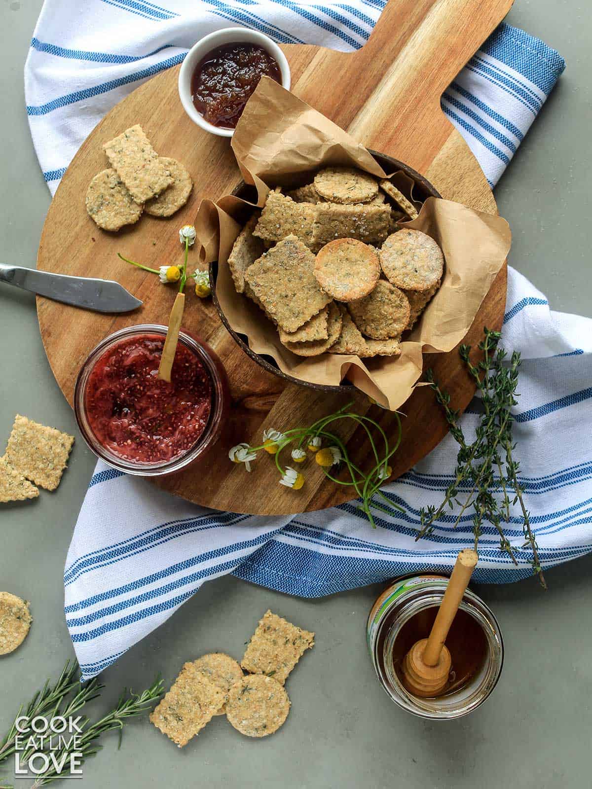 Bowl of soy crackers are garnished with sprig of rosemary and set on burlap scattered with dried soybeans.