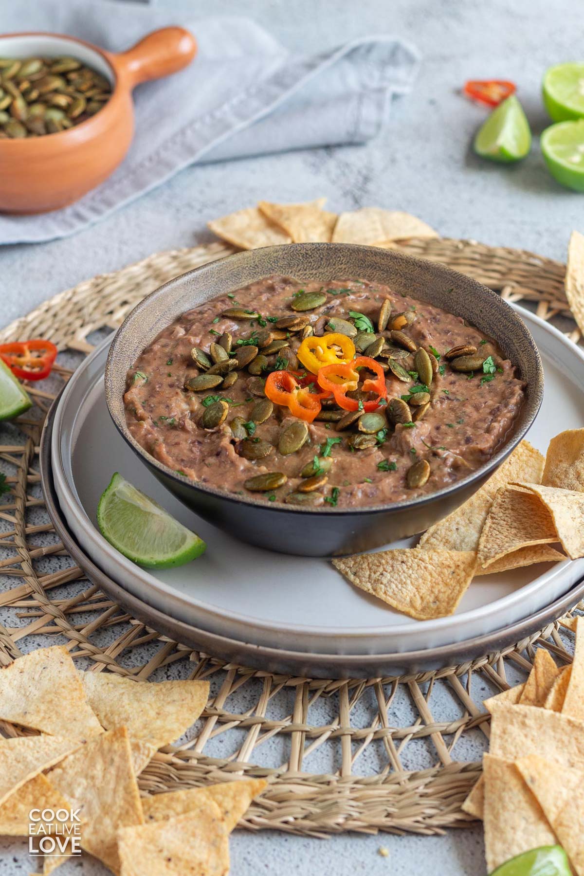 Black bean dip in a bowl on a plate with tortilla chips and lime wedges.