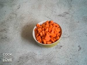 Small bowl filled with carrots diced into small squares.