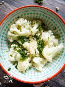 Bowl of steamed cauliflower tossed with garlic and parsley.
