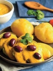 Potatoes topped with huancaina sauce and garnished with olives on a table
