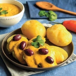 Potatoes topped with huancaina sauce and garnished with olives on a table