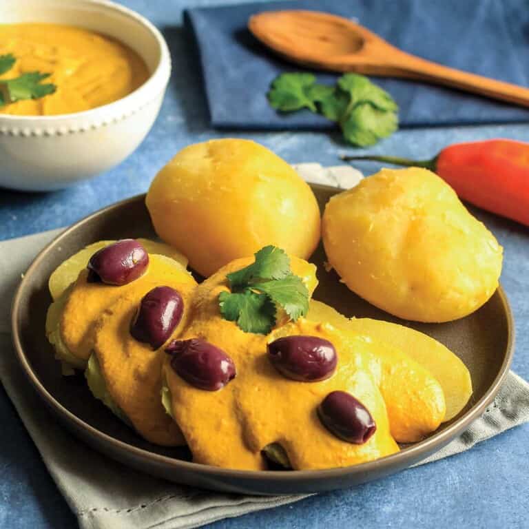 Potatoes topped with sauce, eggs and olives on a table