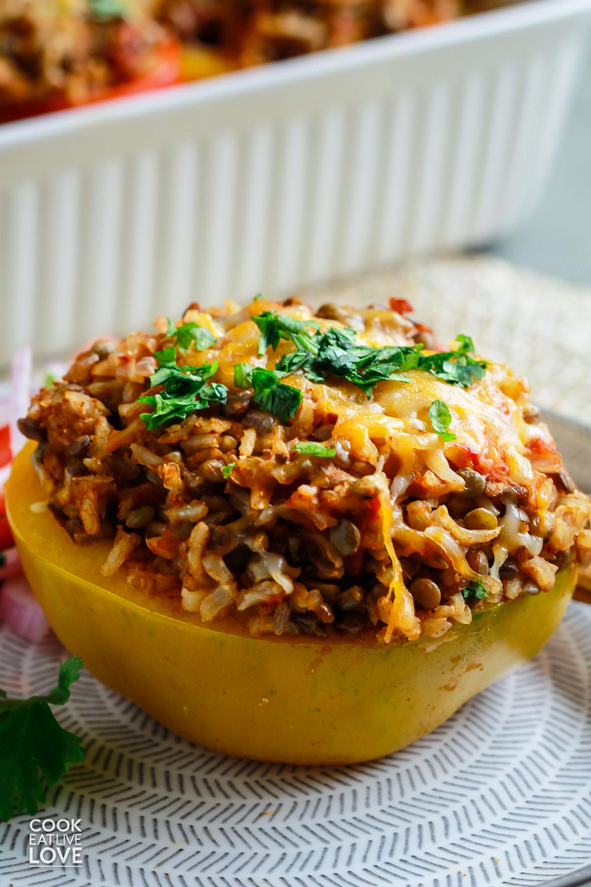 Rice and lentil stuffed peppers on a plate with wooden fork and knife