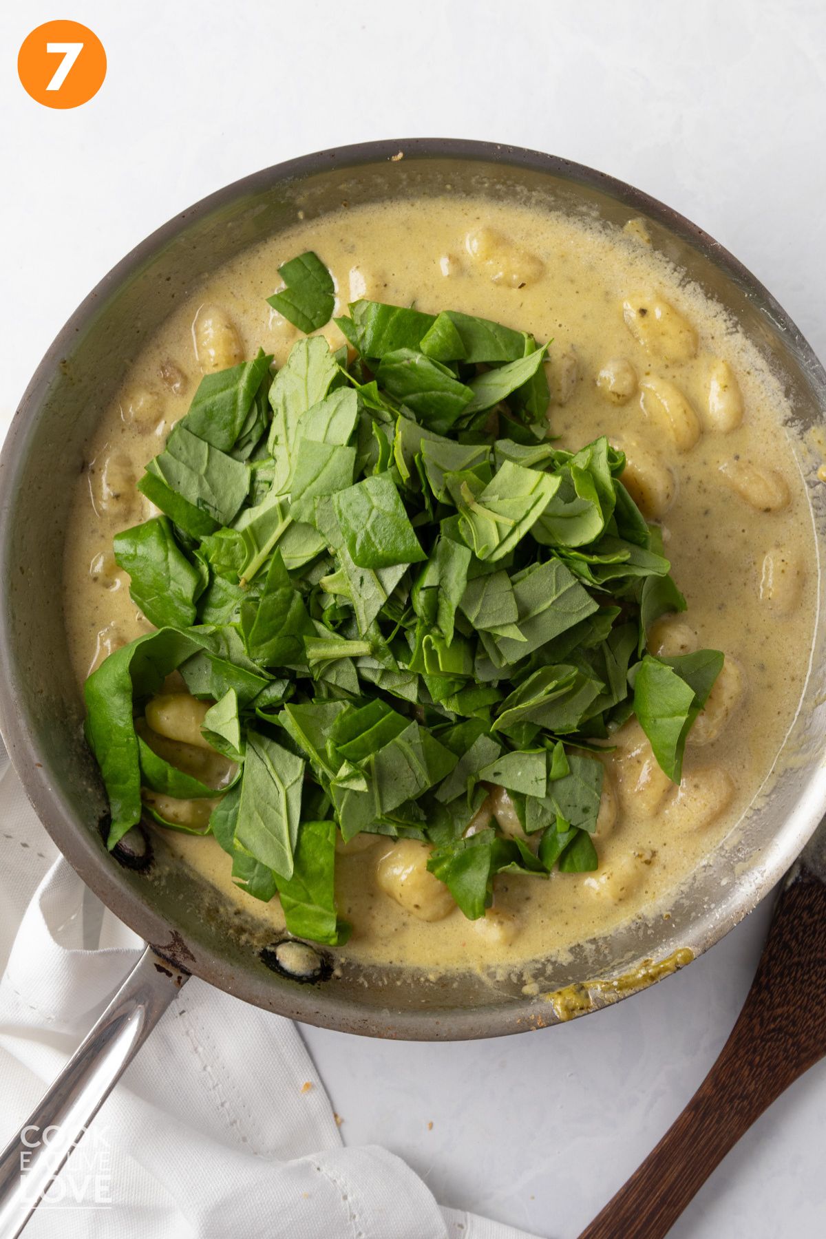Spinach added to the skillet of creamy pesto gnocchi. 