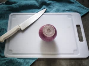 Peeled onion is shown on cutting board.