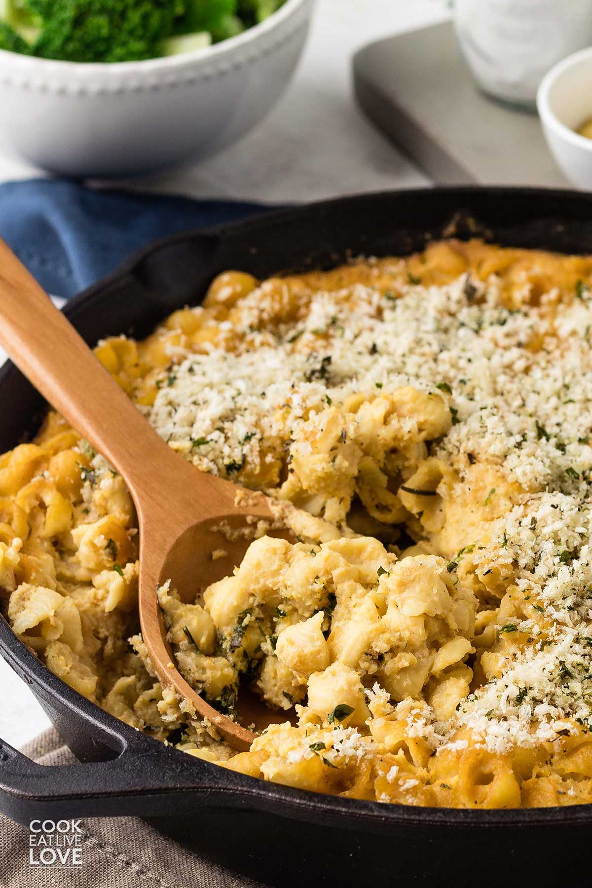 Cast iron skillet mac and cheese with a wooden spoon serving it up.
