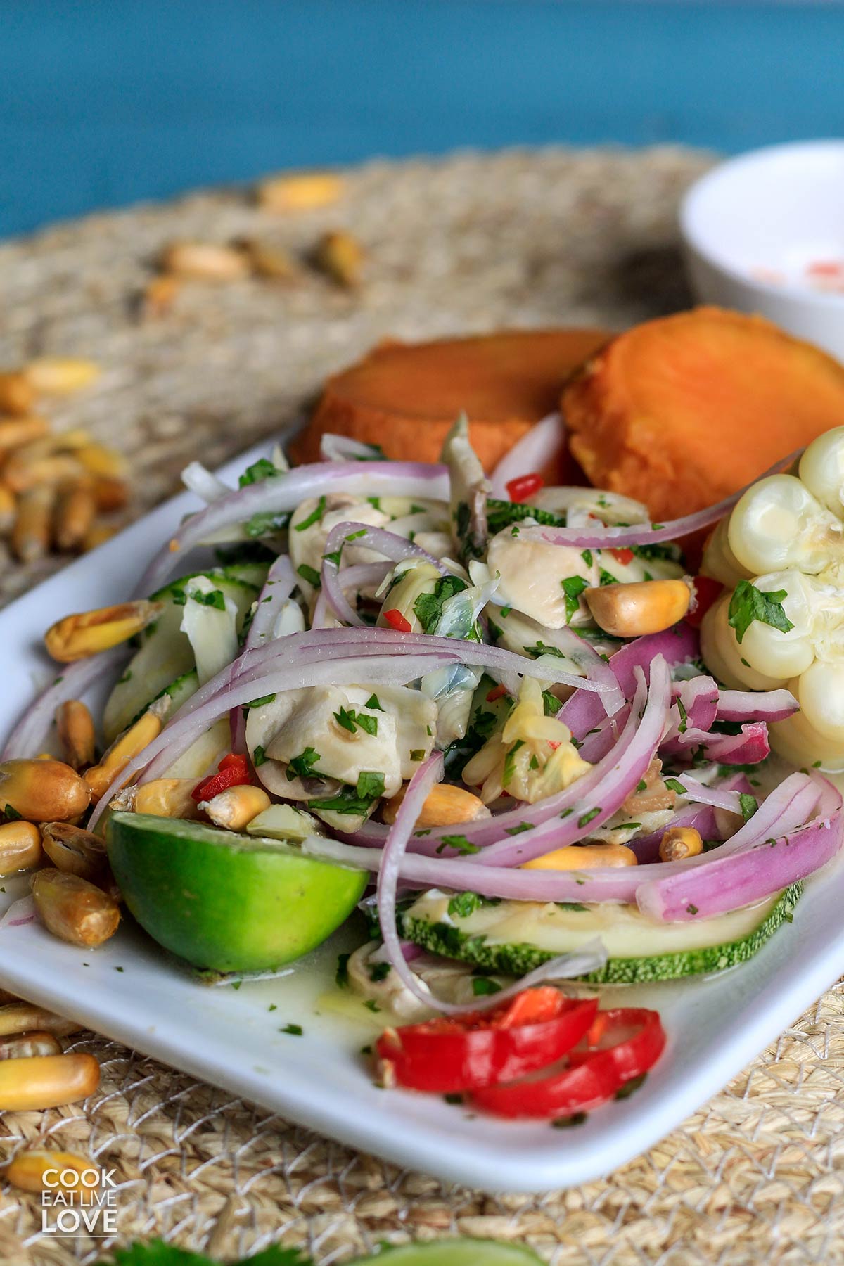 Vegan ceviche on a plate accompanied by sweet potatoes and choclo.