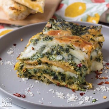 Vegetarian white lasagna on a plate with cheese and red chili flakes.