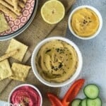 Toast with different colored hummus and vegetable toppings