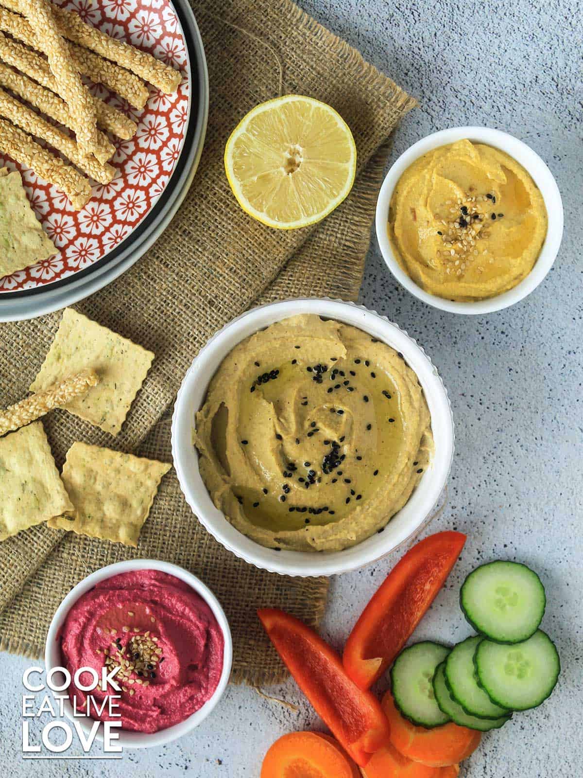 Toast with different colored hummus and vegetable toppings