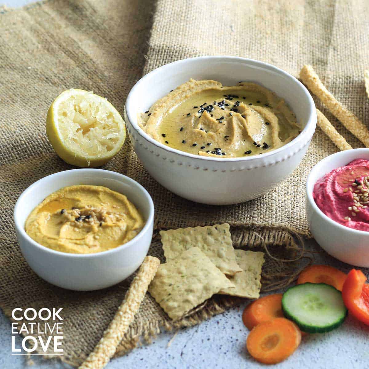 All three easy vegetable hummus served up in white bowls on the table