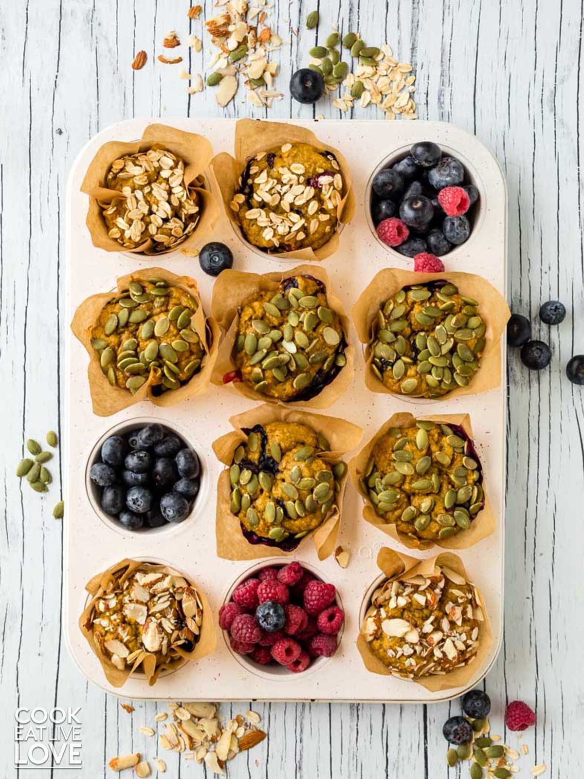 Berry pumpkin muffins are on a cooling rack garnished with fresh berries.