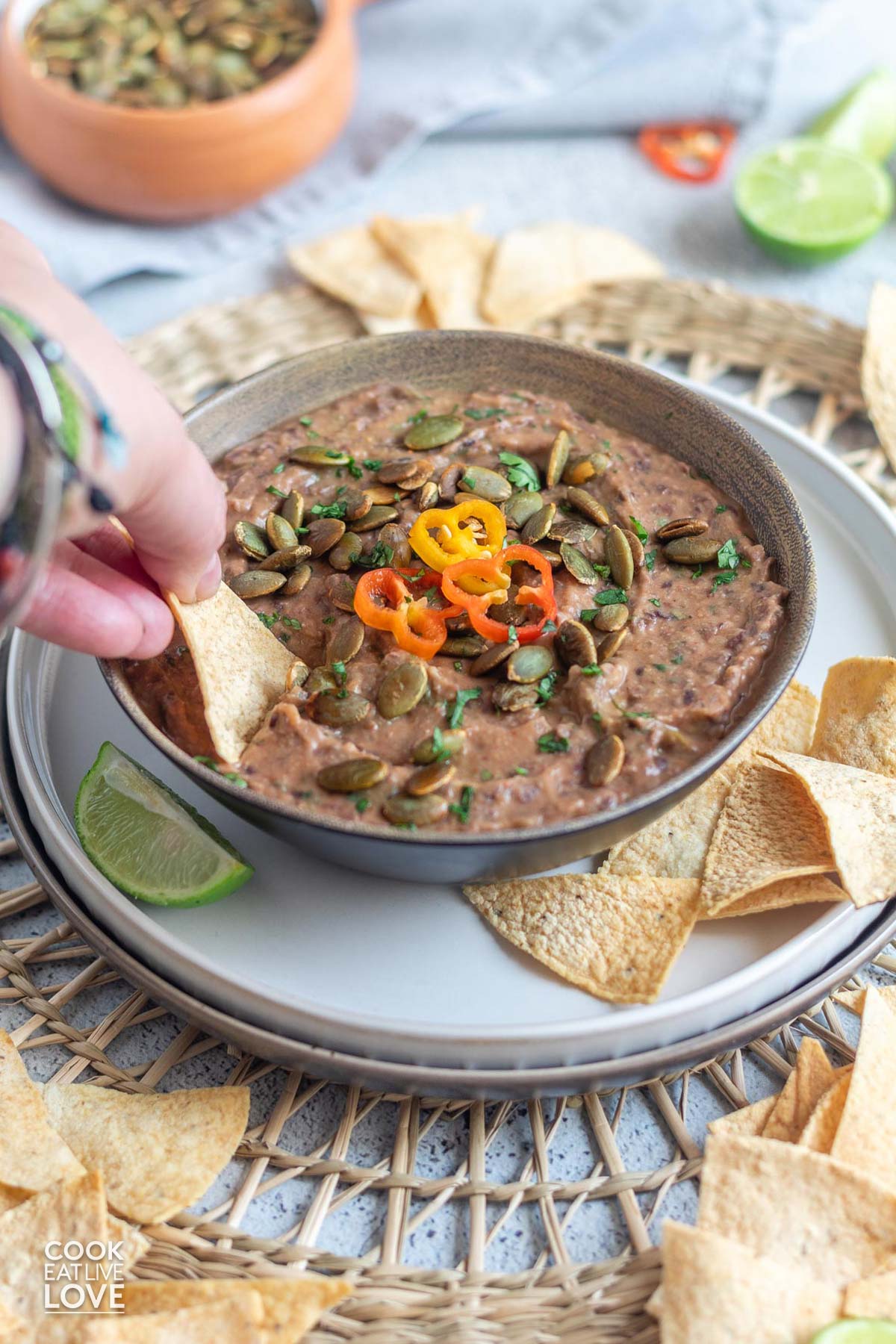 A hand reaching in with a chip to scoop up a bite of black bean dip vegan.
