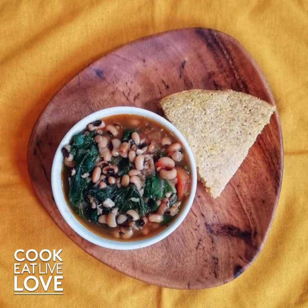 Black-eyed peas in a bowl with slice of cornbread next to it