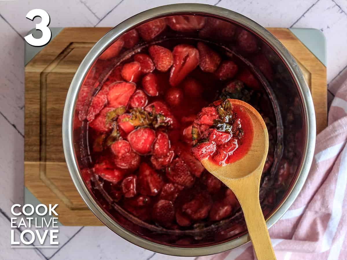 Mixing up the cooked strawberries with a wooden spoon