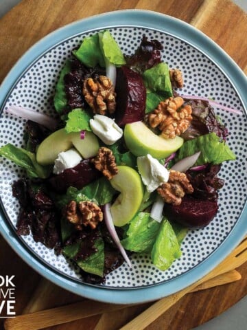 Plate of roasted beetroot salad on wooden cutting board.