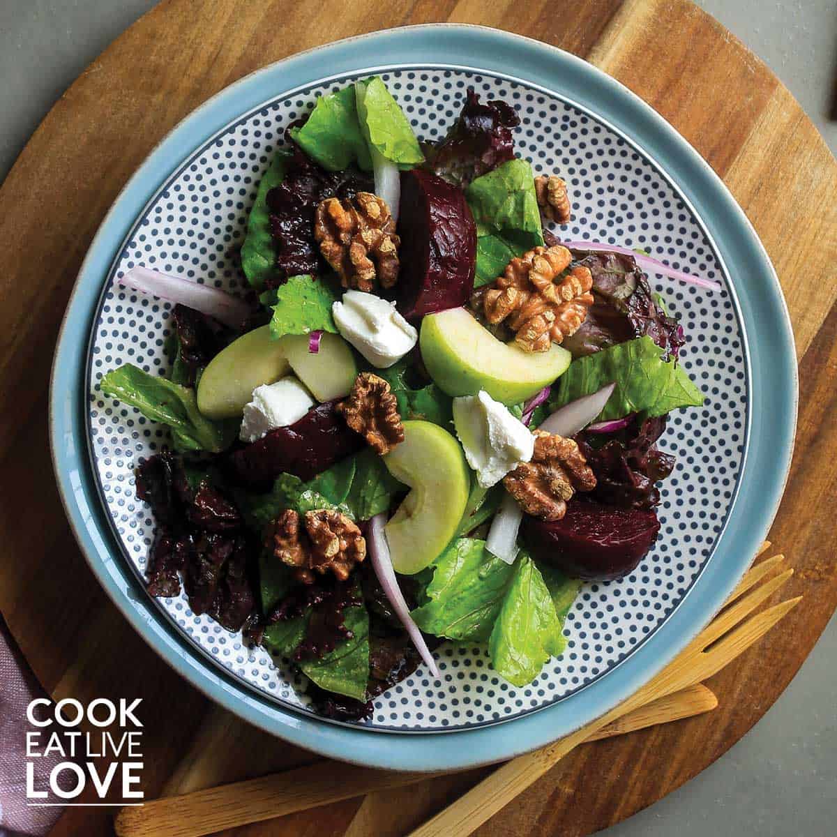 Beet salad in gray bowl on white wooden surface.