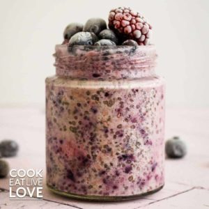 Berry overnight oats topped with frozen berries in jar