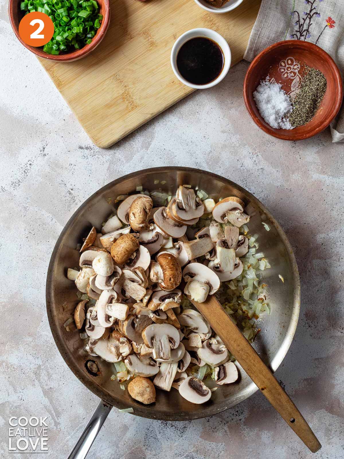 Mushrooms added to the skillet of cooked onions.