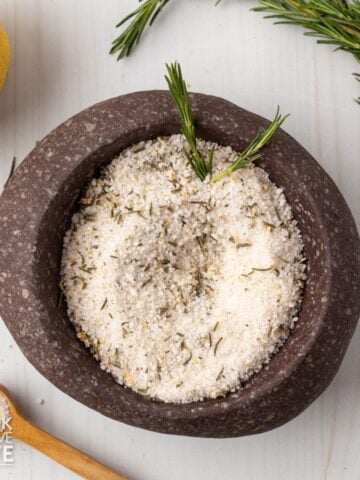 Lemon rosemary salt in a dish garnished with fresh rosemary.