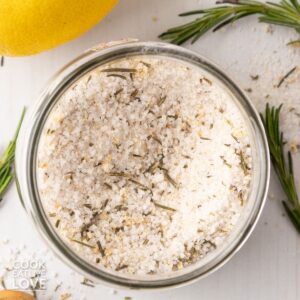 Rosemary salt in a jar with lemon and rosemary scattered around.