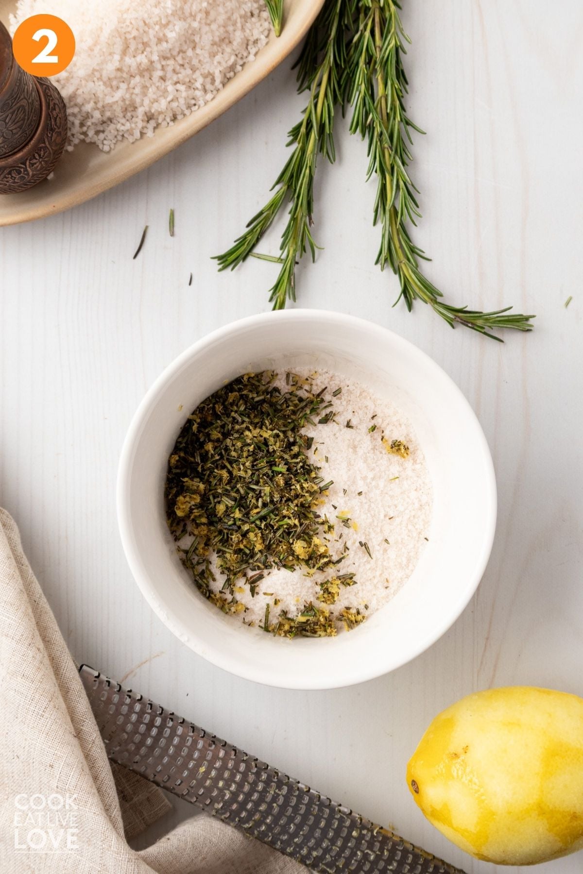 Salt and chopped herbs and lemon added to a bowl. 