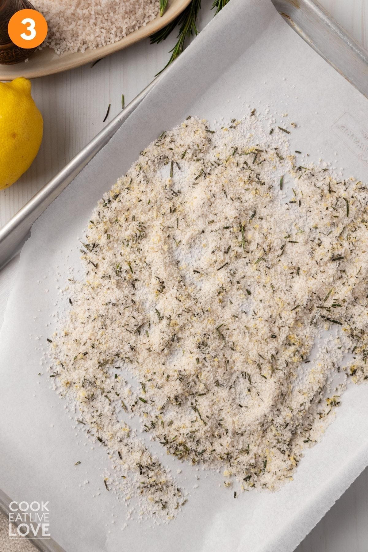 Salt and rosemary mixture spread out on a baking pan. 
