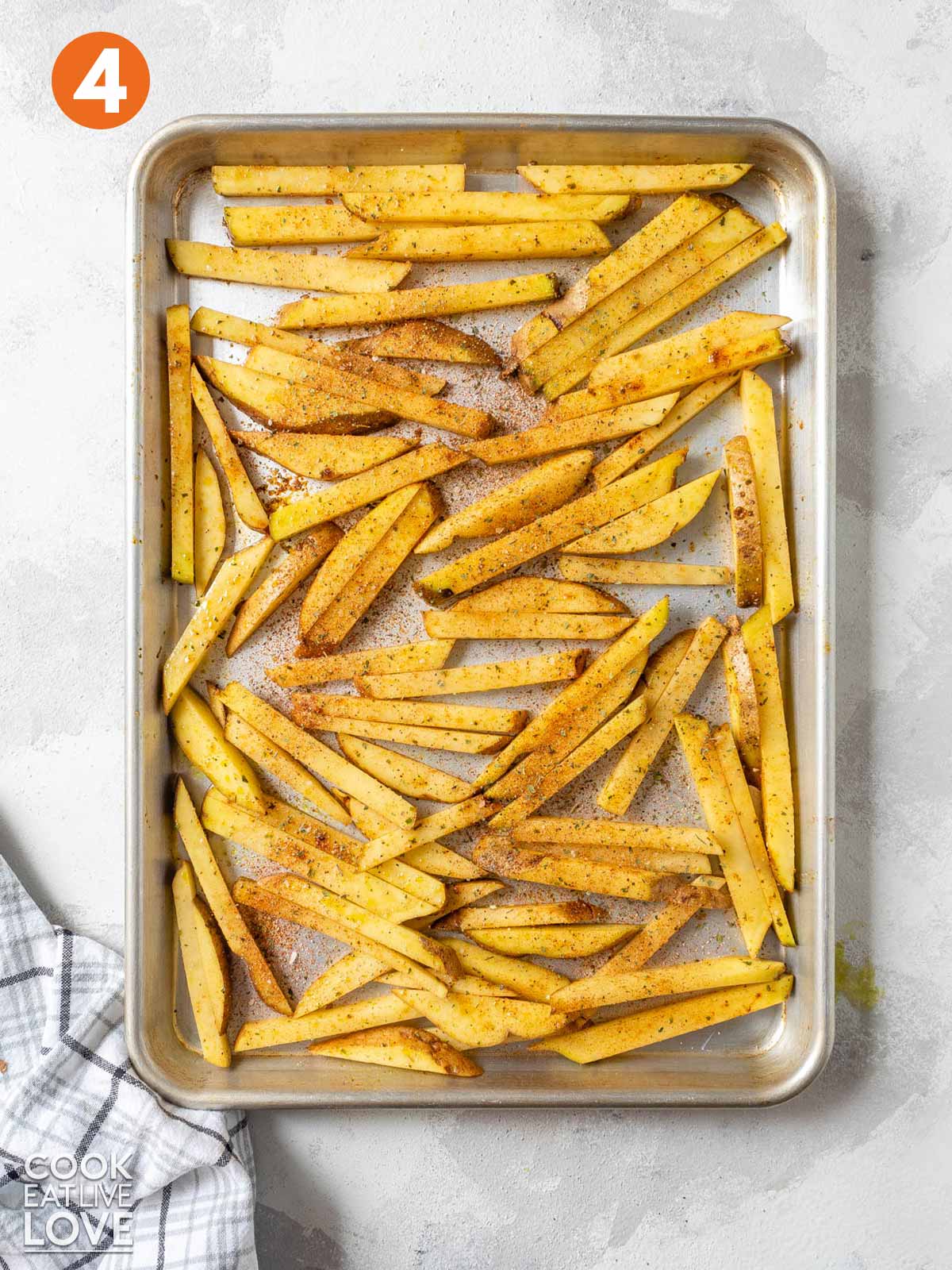 Oven fries on baking sheet with seasoning added on top.