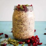 Glass jar of overnight oats with pumpkin seeds and cranberries
