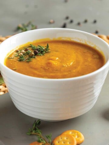 White bowl with carrot soup on table