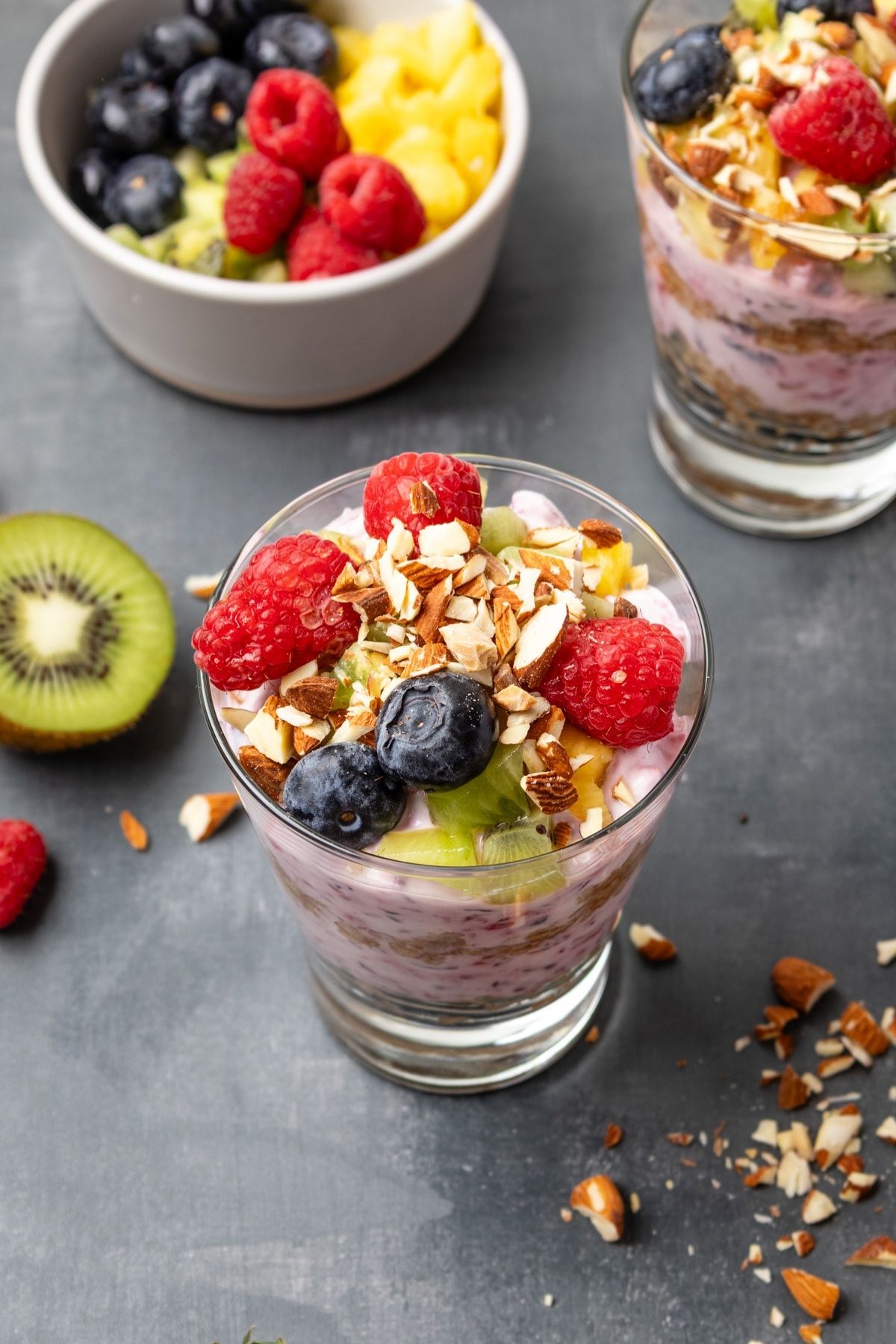 Breakfast parfaits with fruit, oatmeal, and yogurt next to a bowl of fruit.