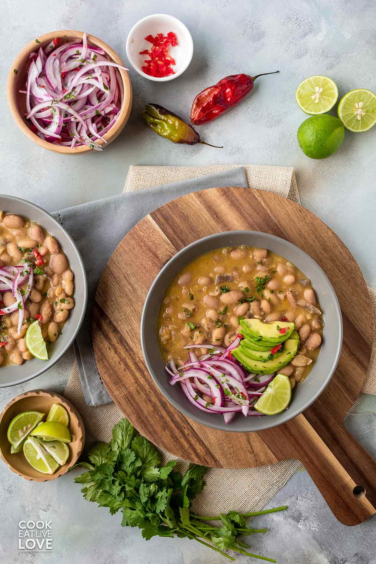 Bowls of peruvian beans served up on the table with salsa criolla, lime wedges and avocado.