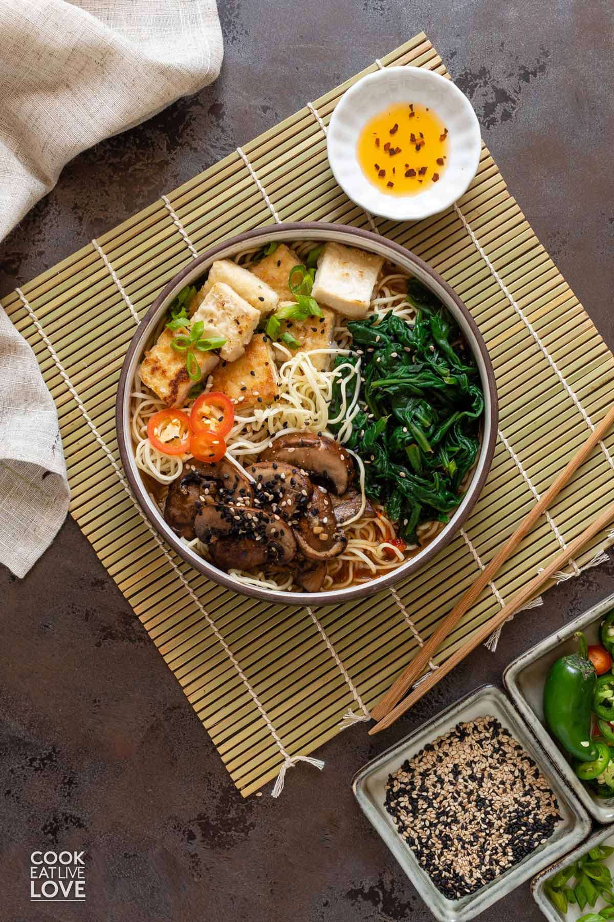 A bowl of vegan tofu ramen in spicy miso broth on the table.