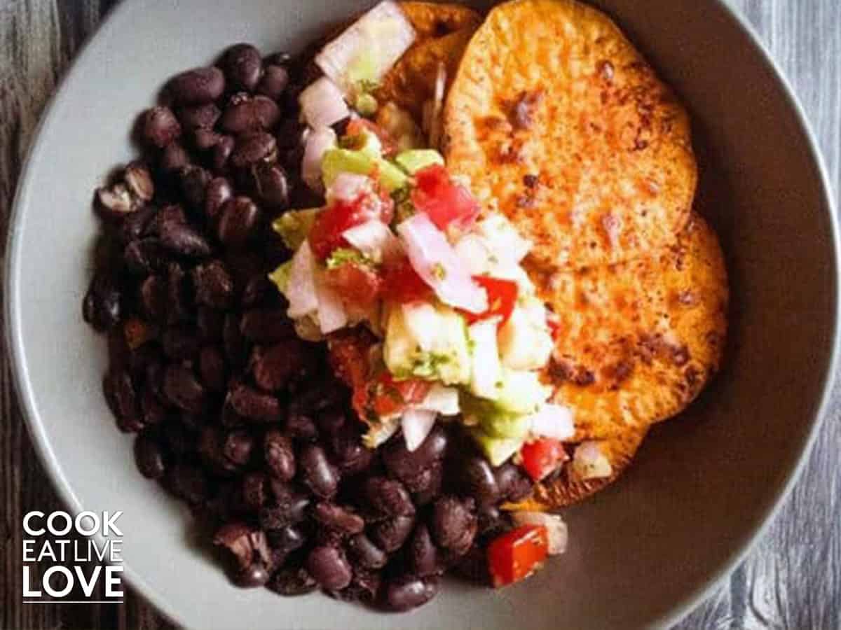 Gray bowl filled with black beans and sweet potatoes topped with salsa