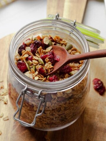 A jar of pumpkin spice granola with a spoon in the jar.