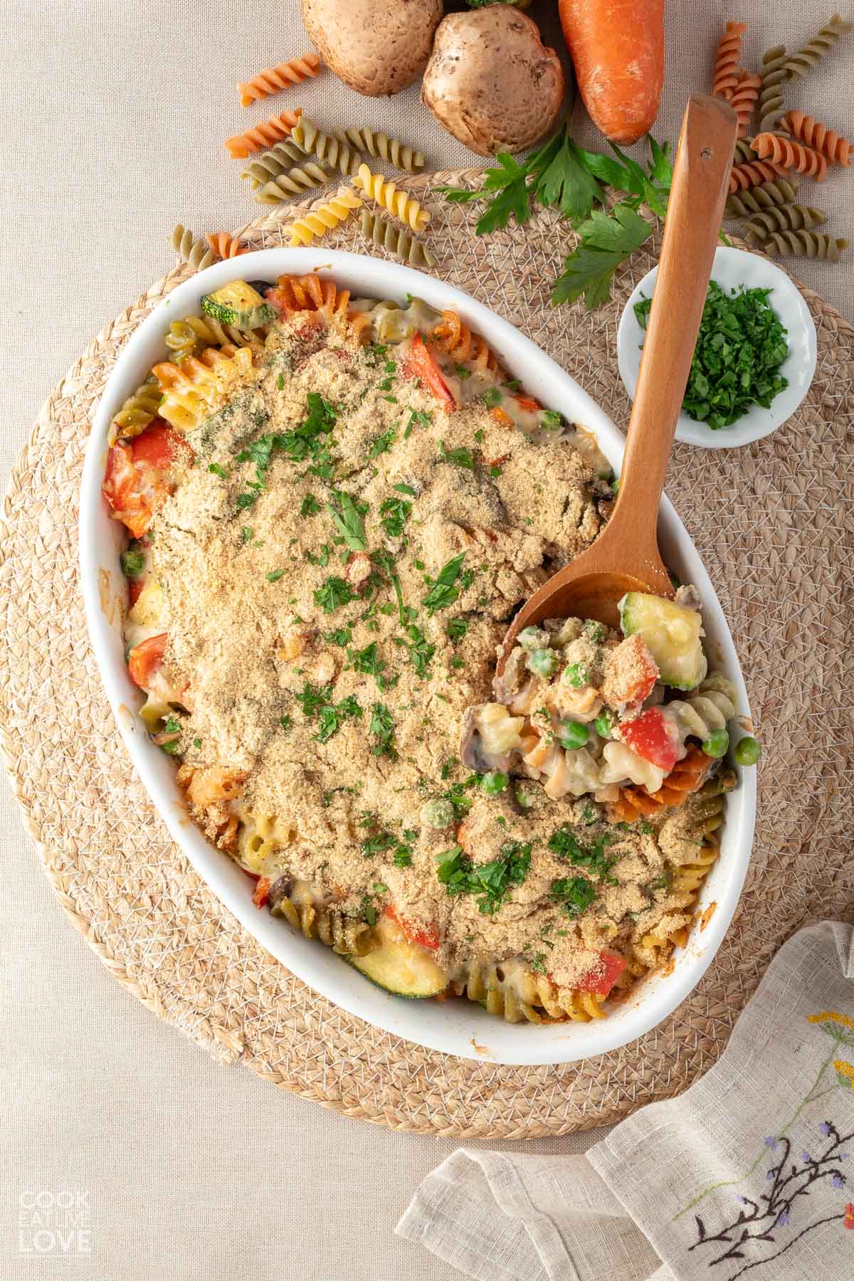 Vegan pasta bake in a casserole dish with a spoon lifting up a serving slightly.