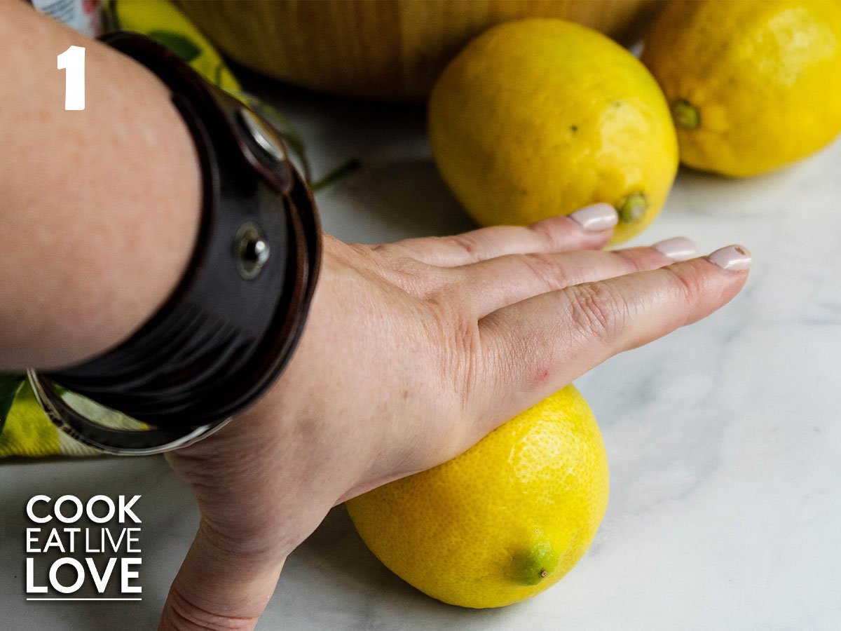 A hand in the picture is pressing down on one of the lemons to demonstrate the rolling of the lemons.