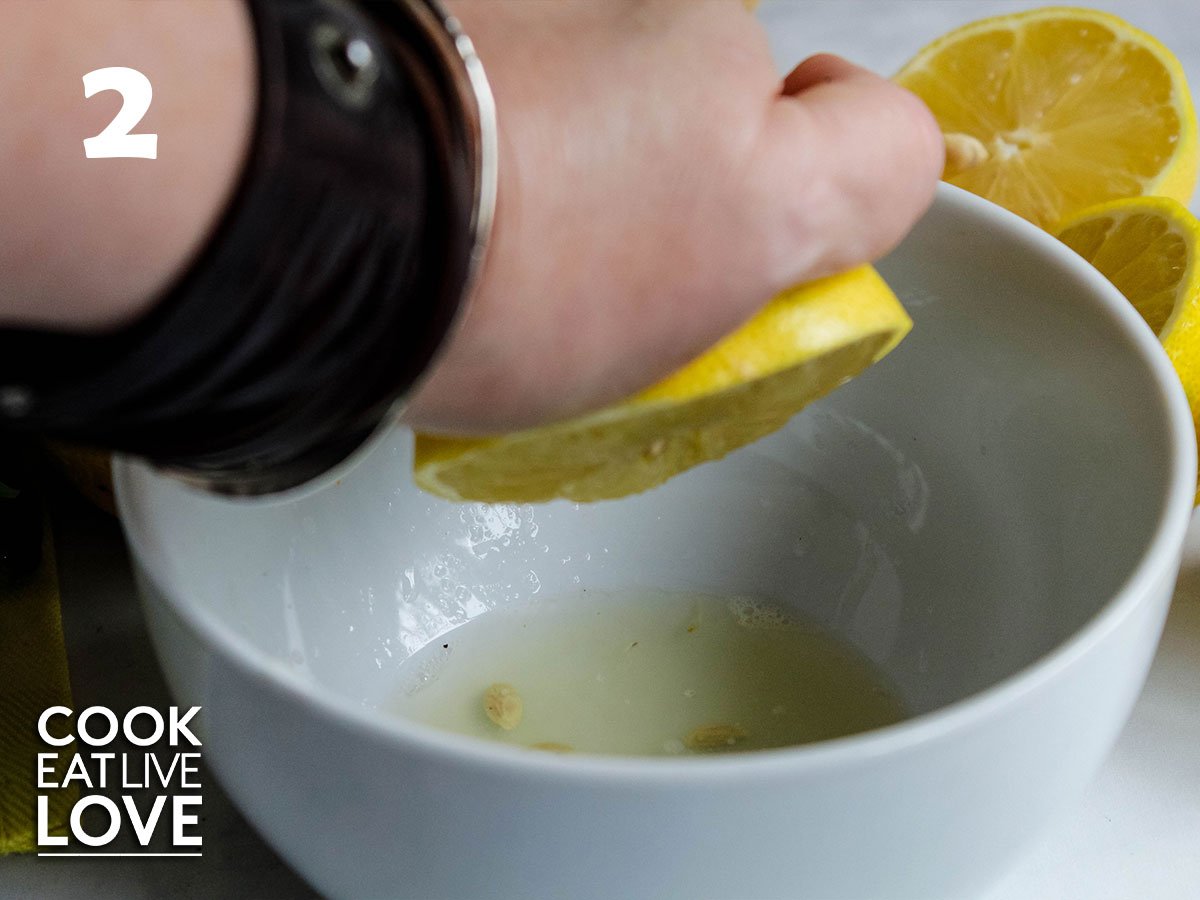 A hand is now squeezing a lemon into a bowl for the cucumber lemonade recipe.