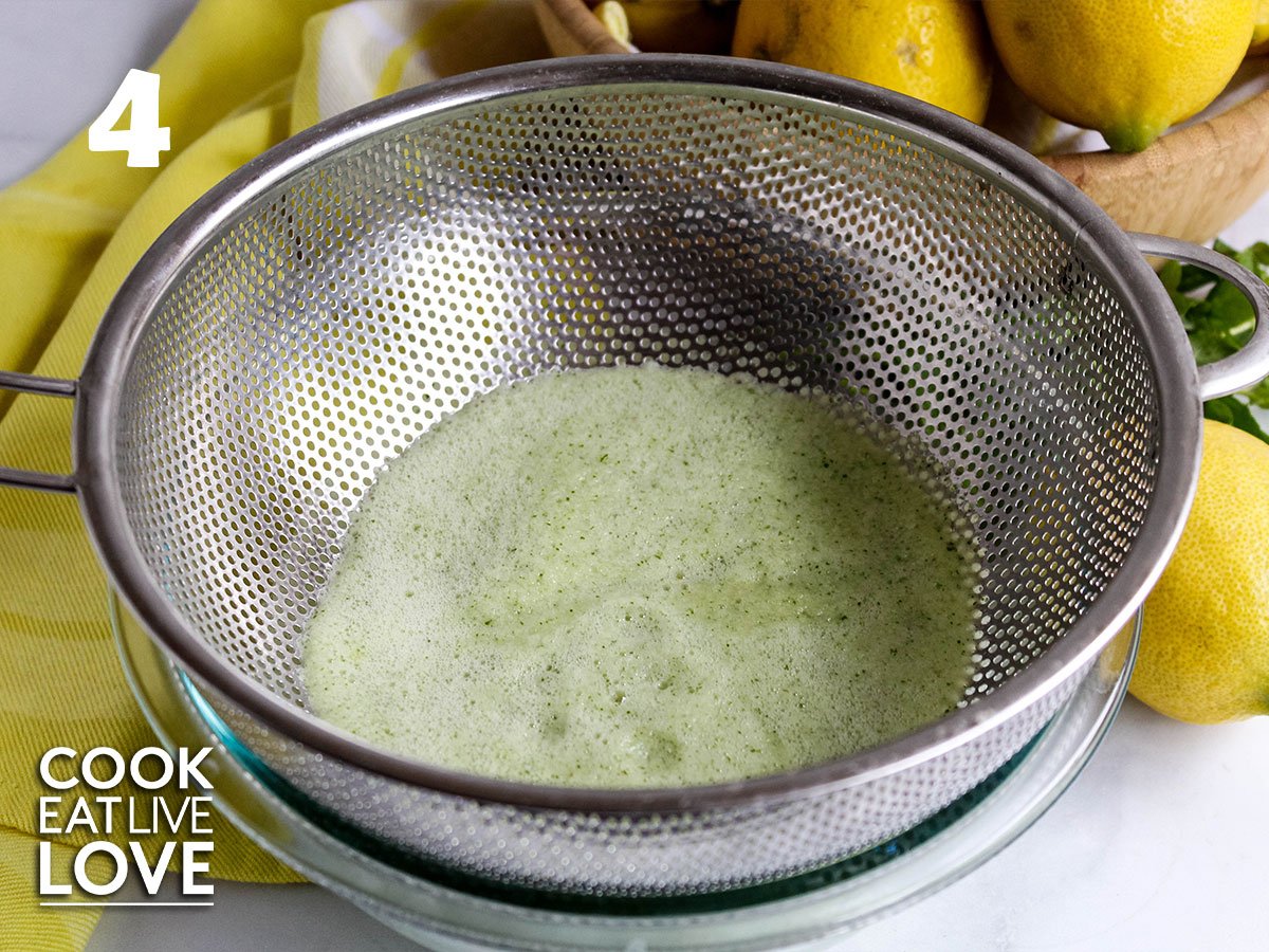 The blended mix is poured into a strainer over a bowl to catch the juice.