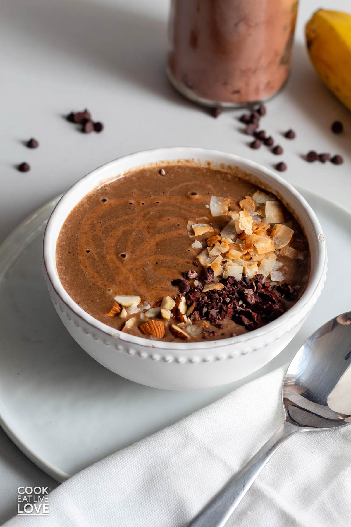 A chocolate smoothie bowl on the table drizzled with almond butter.