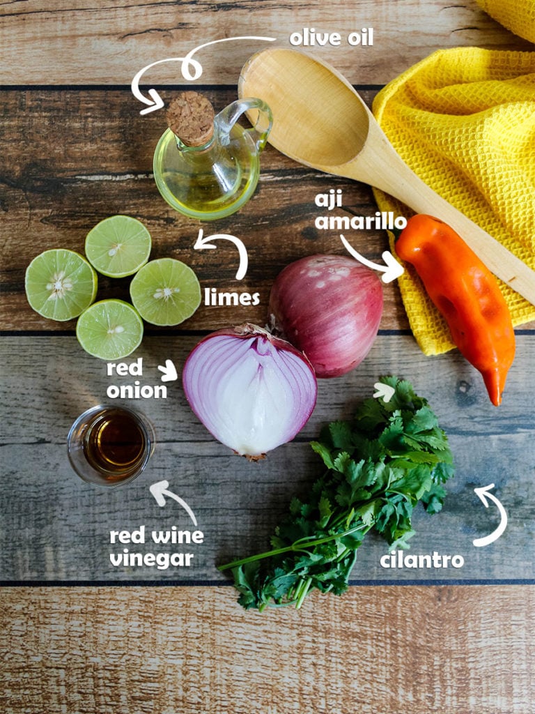 Ingredients for salsa criolla are laid out on the countertop olive oil, aji amarillo, cilantro, red wine vinegar, red onion and limes.